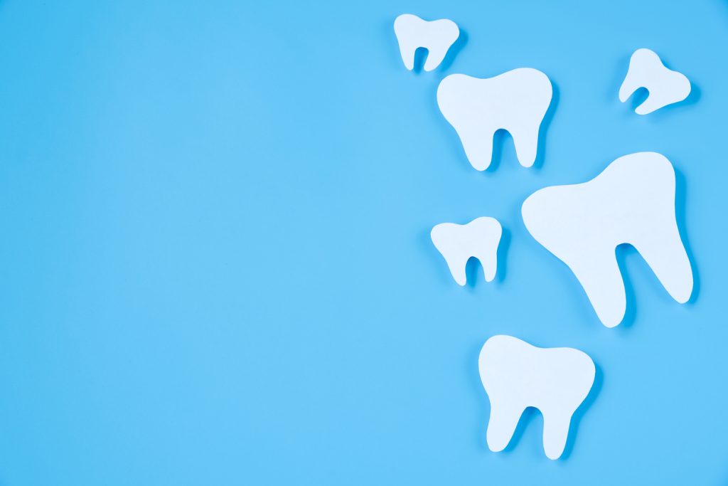 Paper cut mockup of tooth on blue background.