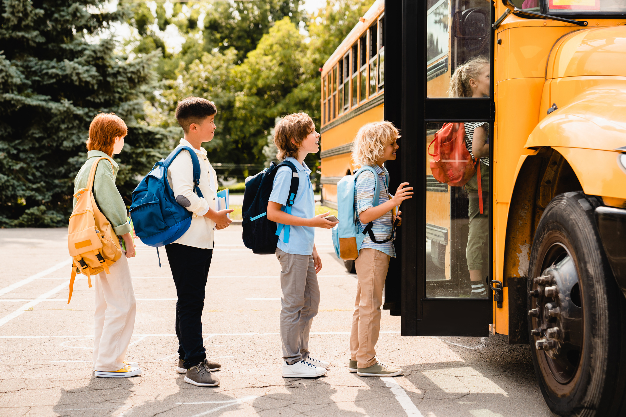 5 school aged children boarding a yellow school bus.