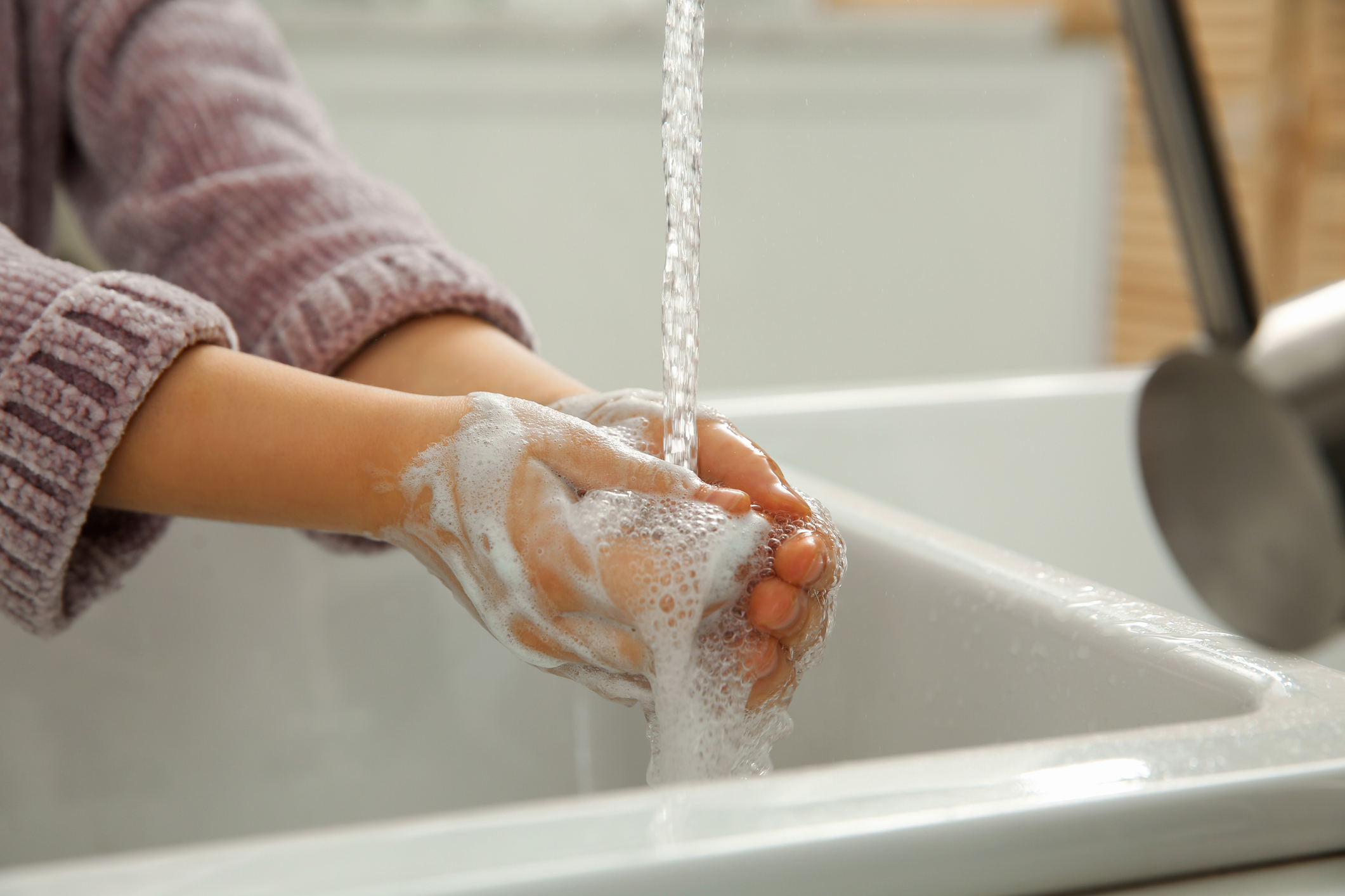 Little girl washing hands with liquid soap at home, closeup